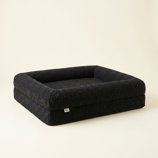 The Chelsea dog bed shown at floor level, calm and low-profile (Onyx boucle)